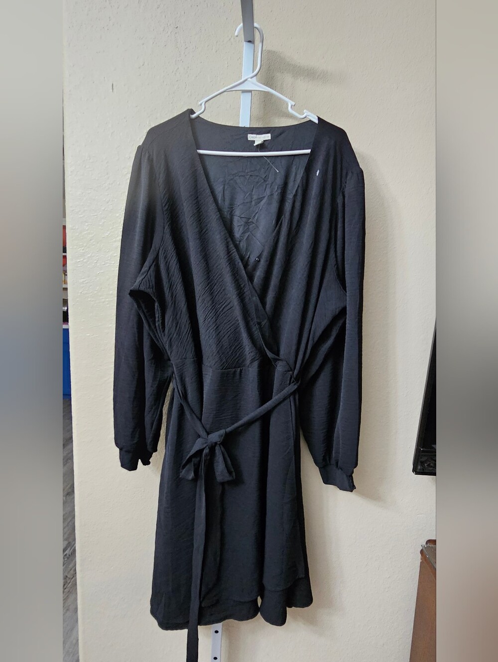 A Cato long-sleeve black wrap dress. It features a deep V-neckline, long sleeves